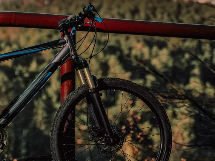 Guidão e quadro de uma bicicleta encostada num corrimão vermelho