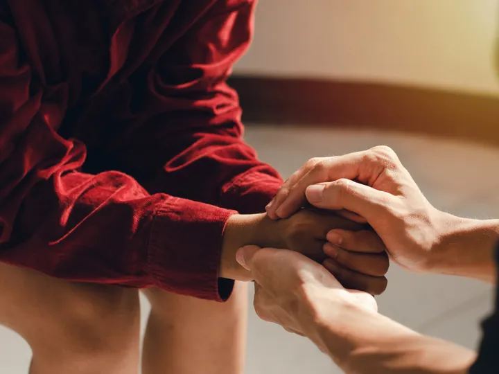 Mãos segurando as mãos de outra pessoa em gesto de apoio